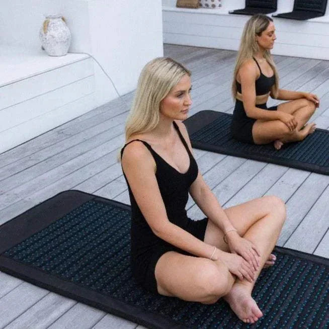 Women using electric PEMF mats with natural amethyst jade for relaxation and meditation.